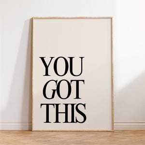 K&ouml;nnte beinhalten: Ein gerahmter Druck mit den Worten "YOU GOT THIS" in fetten schwarzen Buchstaben. Der Hintergrund ist hellbeige und der Rahmen hellbraun. Der Druck lehnt an einer wei&szlig;en Wand.