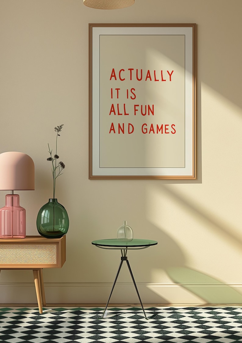May include: A framed print with the text "ACTUALLY IT IS ALL FUN AND GAMES" in red letters. The room features a pink lamp, a green vase, and a small green table with a glass top. The floor has a black and white checkered pattern.