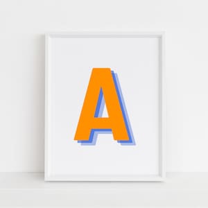 May include: A white framed print with a large orange letter "A" in a blue outline.
