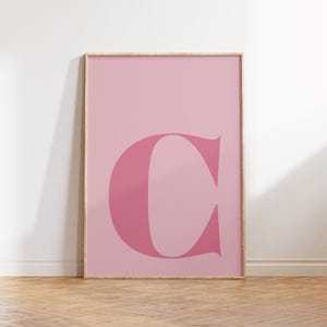 Puede incluir: Un p&oacute;ster rosa enmarcado con una gran letra "C" rosa y audaz en el centro.