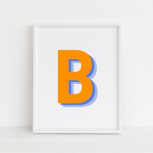 Può includere: Una stampa incorniciata bianca con una grande lettera arancione "B" in un contorno blu. La lettera è centrata su uno sfondo bianco.