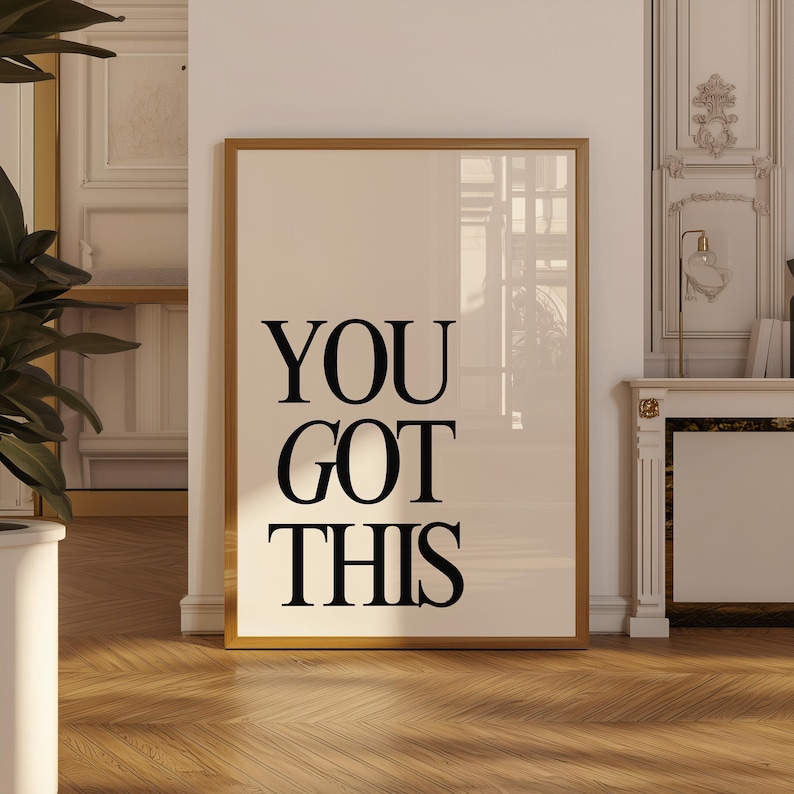 K&ouml;nnte beinhalten: Gerahmter Druck mit den Worten "YOU GOT THIS" in fetten schwarzen Buchstaben. Der Druck hat einen cremefarbenen Hintergrund und einen goldfarbenen Rahmen. Der Druck wird in einem Raum mit Parkettboden und einer wei&szlig;en Wand angezeigt.