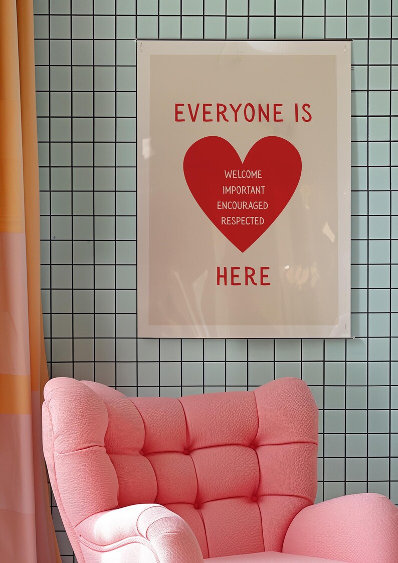 May include: A framed poster with the words "EVERYONE IS HERE" in red, with a red heart graphic. Below the heart are the words "WELCOME, IMPORTANT, ENCOURAGED, RESPECTED." A pink armchair is in the foreground, and the background is a light blue tiled wall.