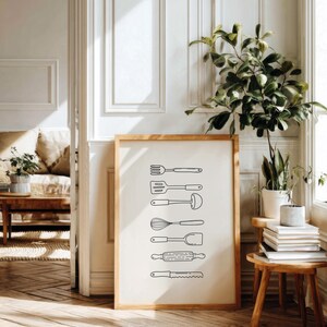 May include: A framed print featuring line drawings of kitchen utensils, including a fork, spatula, ladle, whisk, spoon, rolling pin, and serrated knife. The artwork is in a wooden frame, set against a neutral background.