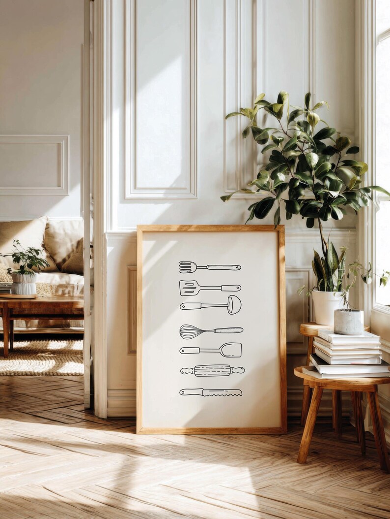 May include: A framed print featuring line drawings of kitchen utensils, including a fork, spatula, ladle, whisk, spoon, rolling pin, and serrated knife. The artwork is in a wooden frame, set against a neutral background.