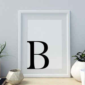 May include: A white framed print with a black letter "B" in a bold font.