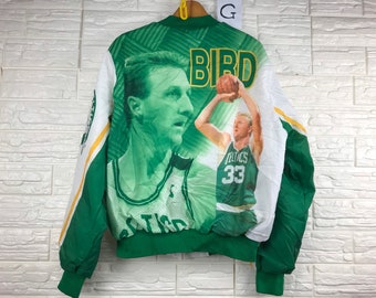 May include: Green and white reversible jacket with a basketball player on the front. The jacket has a zipper closure and a stand-up collar. The text "BIRD" is printed on the front of the jacket.