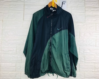 May include: A black and green windbreaker jacket with a zipper closure and a Nike swoosh logo on the chest.