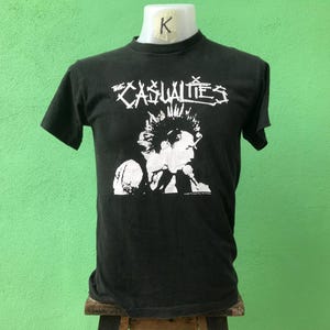 May include: Black t-shirt with a white graphic of a punk rock band called "The Casualties".