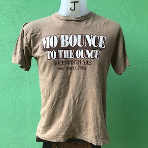 May include: A tan t-shirt with the text "Mo' Bounce to the Ounce" in white letters. The text "Soul Brotha No. 2 Soul Party 2003" is printed in brown letters below the main text.