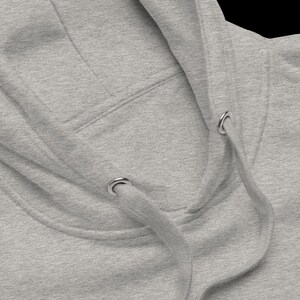 May include: Close-up of a gray hooded sweatshirt with a drawstring. The drawstring has two metal eyelets.