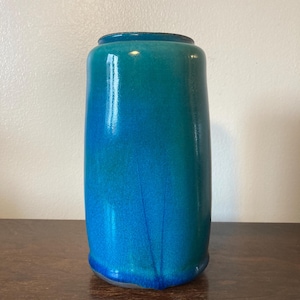 Könnte beinhalten: Eine tealblaue Keramikvase mit abgerundetem Boden und leicht ausgestelltem oberen Rand.