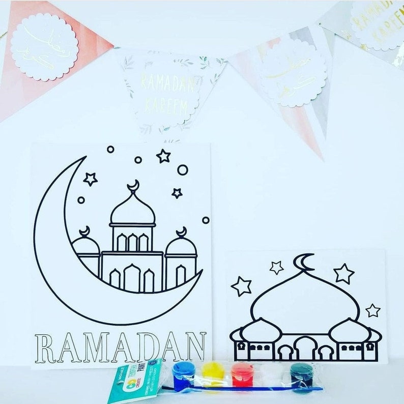 May include: Two white canvas boards with black outlines of a mosque and crescent moon. The larger board says "RAMADAN" at the bottom. The smaller board has a mosque with a crescent moon on top. Both boards are accompanied by a set of four paint pots and a paintbrush.
