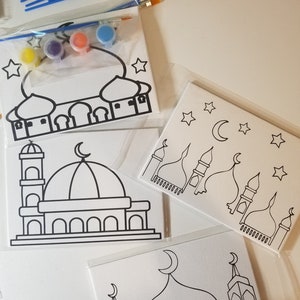 May include: A set of three paint-by-number canvases featuring mosque designs. Each canvas has a different mosque design with black outlines and white backgrounds. The set includes four small bottles of paint in yellow, purple, orange, and blue.