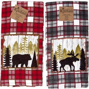 May include: Two rectangular terry towels featuring a plaid pattern and a rectangular patch with a forest scene. The left towel is red and white with a black bear silhouette. The right towel is gray, red, and white with a black moose silhouette.