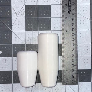 Puede incluir: Dos pomos de cambio blancos, uno ligeramente m&aacute;s grande que el otro. El pomo m&aacute;s grande tiene 12,7 cm de alto. El pomo m&aacute;s peque&ntilde;o tiene 8,9 cm de alto.