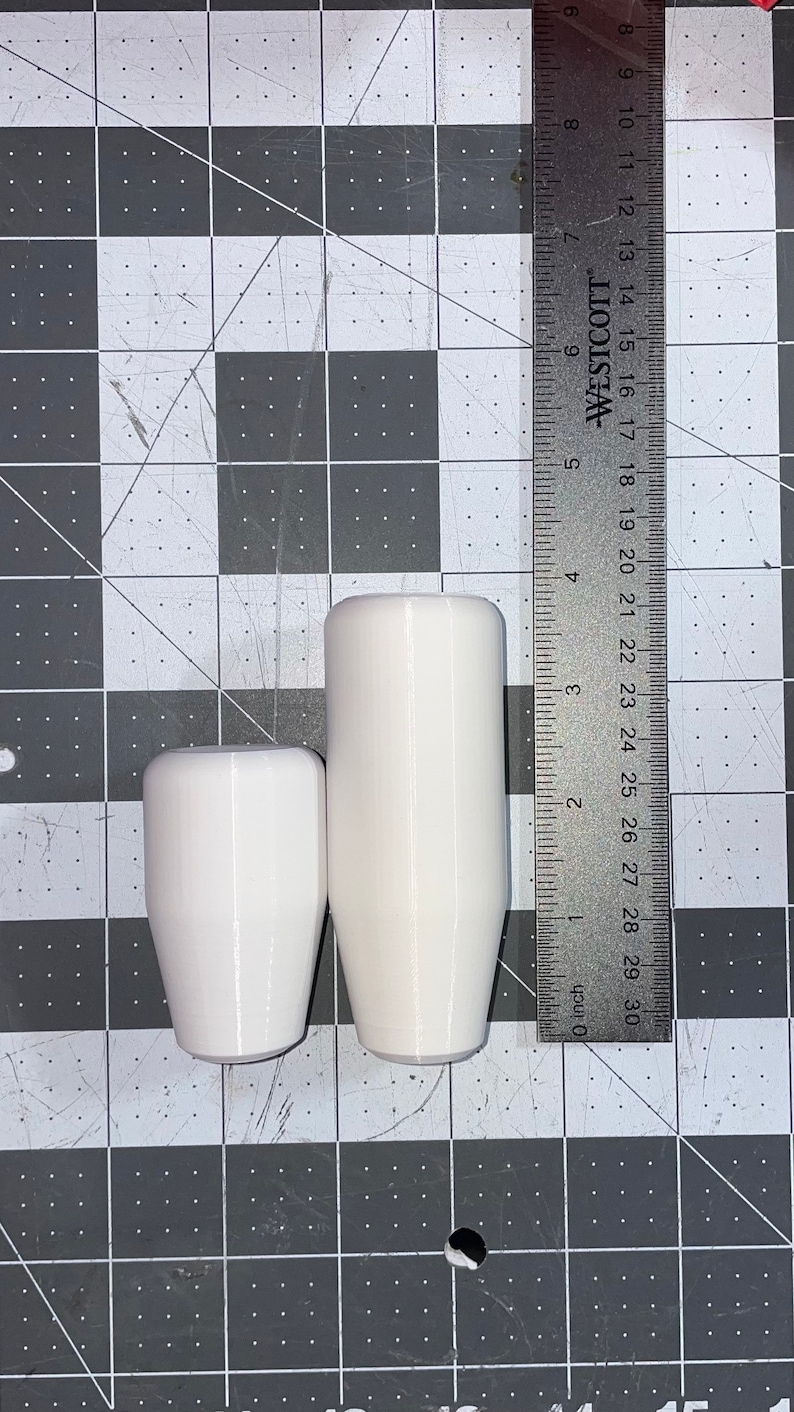 Puede incluir: Dos pomos de cambio blancos, uno ligeramente m&aacute;s grande que el otro. El pomo m&aacute;s grande tiene 12,7 cm de alto. El pomo m&aacute;s peque&ntilde;o tiene 8,9 cm de alto.