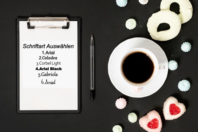May include: A clipboard with a list of fonts to choose from: Arial, Caladea, Corbel Light, Arial Black, Gabriola, and Script. The clipboard is on a black surface with a cup of coffee, a pen, and meringue cookies.