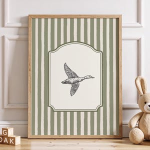 Peut inclure: Tableau encadr&eacute; avec une illustration en noir et blanc d'un canard en vol. L'&oelig;uvre d'art est plac&eacute;e sur un fond cr&egrave;me avec une bordure d&eacute;corative et un motif &agrave; rayures vertes et blanches. Le cadre est en bois.