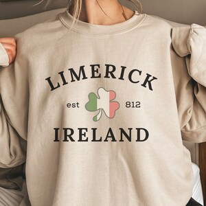 May include: A beige sweatshirt with the text "LIMERICK est 812 IRELAND" and a green shamrock with a red and white center.