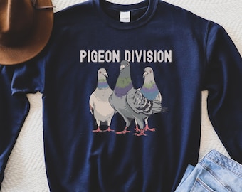 May include: Navy blue sweatshirt with the text "PIGEON DIVISION" above a graphic of three pigeons. The pigeons are in shades of gray, white, and blue, with red feet. The sweatshirt is a casual style.