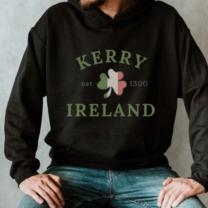 Op de afbeelding: Zwarte hoodie met een groene klaver en de tekst "Kerry est 1300 Ierland" gedrukt op de voorkant.