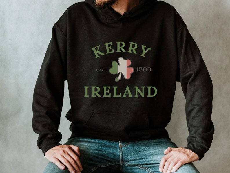 Op de afbeelding: Zwarte hoodie met een groene klaver en de tekst "Kerry est 1300 Ierland" gedrukt op de voorkant.