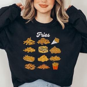 Pu&ograve; includere: Felpa nera con la parola "Fries" in lettere bianche e una variet&agrave; di diversi tipi di patatine fritte illustrate in giallo e marrone.