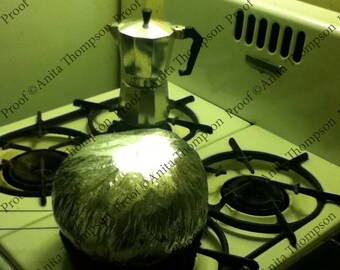 Black and white photo of coffee maker with a Jiffy pop on a vintage stove