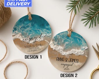 Könnte beinhalten: Zwei runde Ornamente mit einem Strandmotiv. Die obere Hälfte ist türkis, die untere Hälfte ist beige, mit weißen Wellen dazwischen. Eines sagt "engaged" mit Namen und Datum. Das andere sagt "engaged" mit Namen und dem Jahr 2025.