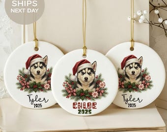 May include: Three round white Christmas ornaments with a gold string for hanging. Each ornament features a husky dog wearing a Santa hat, surrounded by festive greenery and candy canes. The names "Tyler" and "Chloe" are printed on the ornaments, along with the year "2025".