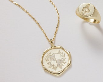 Peut inclure: Un collier en or avec un pendentif en forme de bouclier orné d'une couronne de laurier. Une bague signet en or assortie avec un blason est également représentée.