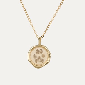 May include: A gold chain necklace with a small, round pendant featuring a paw print design.