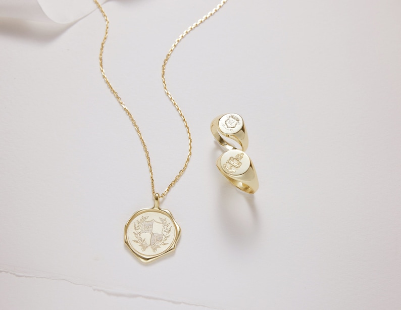 Peut inclure: Un collier en or avec un pendentif repr&eacute;sentant un blason d&eacute;taill&eacute;. Deux bagues signet en or avec des motifs grav&eacute;s sont &eacute;galement repr&eacute;sent&eacute;es.