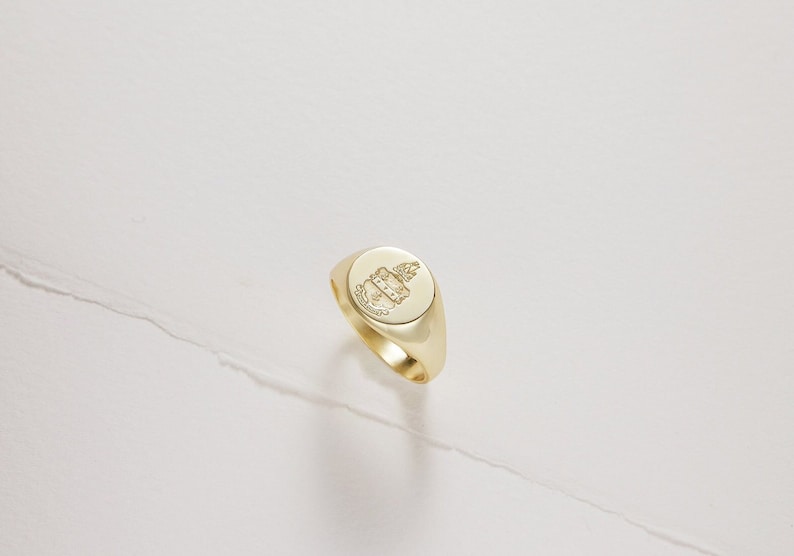 Peut inclure: Une bague signet en or avec un blason grav&eacute; d&eacute;taill&eacute; sur le dessus.