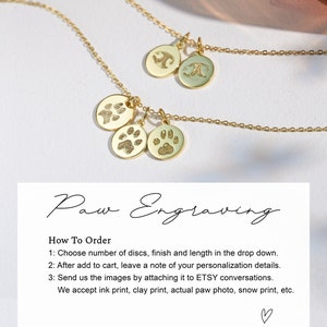 May include: Gold necklace with three round pendants featuring paw prints. The necklace is on a white background with text that reads "Paw Engraving" and instructions on how to order.
