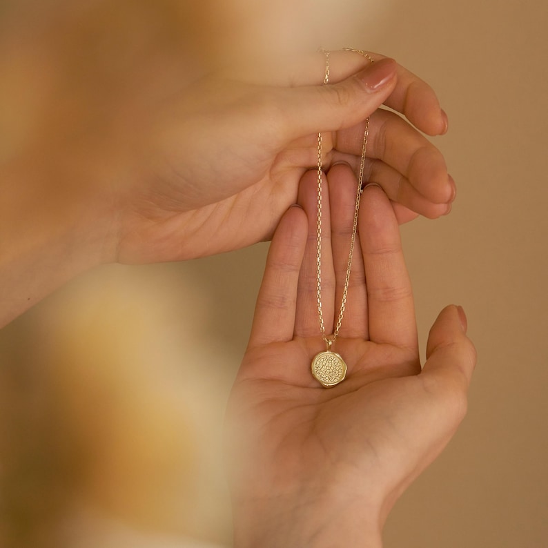 May include: A gold chain necklace with a round pendant featuring a detailed geometric design.