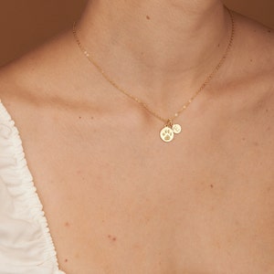 May include: A gold chain necklace with two charms: a paw print and a letter 'E'.