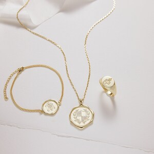 Peut inclure: Trois colliers en or avec une cha&icirc;ne d&eacute;licate et un pendentif circulaire orn&eacute; d'un motif floral. Le pendentif est grav&eacute; d'un blason.