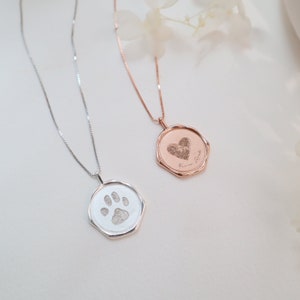 May include: Two silver necklaces with pendants. One pendant is a silver octagon with a paw print engraved inside. The other pendant is a rose gold octagon with a heart engraved inside. The rose gold pendant has the text "You are my best friend" engraved on it.