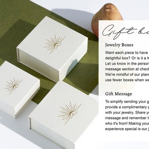 May include: Three white gift boxes with a sun and moon logo. The boxes are made of a textured paper and have a subtle gold color. The text on the image reads "Gift box", "Jewelry Boxes", "Want each piece to have its own delightful box? Or is it a heartfelt gift? Let us know in the personalization or message section at checkout. We're mindful of our planet and aim to use fewer boxes when we can." and "Gift Message", "To simplify sending your gift, we provide a complimentary gift card with your jewelry. Share your message and remember to tell us who it's from! Making your gift-giving experience special is our joy."