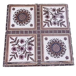 May include: Square decorative tile with a floral design. The tile is divided into four squares, each featuring a different floral pattern in shades of brown, pink, and white. The edges are bordered with a repeating geometric pattern.