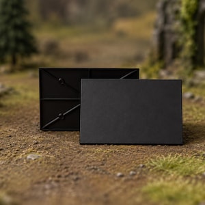 May include: A rectangular black plastic display base with a smooth top surface and a structural support grid visible on the back panel. The object features a clean, matte finish and a simple geometric design, providing a stable platform for small items.