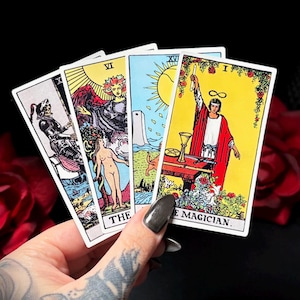 Peut inclure: Quatre cartes de tarot sont présentées, avec des illustrations et des titres colorés. Les cartes comprennent des images d'un squelette, d'une femme, d'une tour et d'une figure intitulée "LE MAGICIEN". Les cartes sont tenues sur un fond sombre avec des roses rouges.