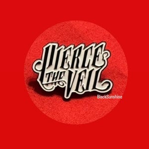 May include: A white and black enamel pin with the text "Pierce the Veil" in a stylized font. The pin is set against a red background with a circular shape. The text "BlackSunshine" is in the bottom right corner.