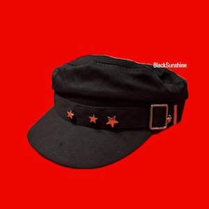 May include: Black cap with a short brim and a decorative band. The band features three star-shaped embellishments and a silver-colored buckle. The text "BlackSunshine" is visible on the cap. This hat is a stylish accessory.