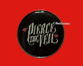 Pode incluir: Um botão redondo preto com a frase "Pierce the Veil" em branco. Dois corações rosa em ambos os lados do texto. O botão tem uma borda prateada e um fundo vermelho.