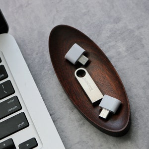 May include: Two silver USB adapters with white plastic casings, one with the text "Kingston" printed on it, are sitting in a wooden oval dish.