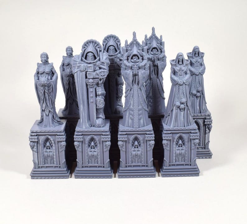 Puede incluir: Colecci&oacute;n de estatuas grises en miniatura, cada una con dise&ntilde;os intrincados de t&uacute;nicas detalladas y bases arquitect&oacute;nicas. Las estatuas var&iacute;an en forma, representando figuras con cascos, capuchas y atuendos ornamentados, adecuadas para juegos de mesa o exhibici&oacute;n.