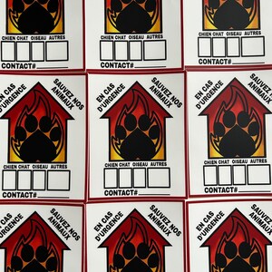 May include: Nine red and yellow stickers with a black paw print inside a house shape. The stickers say "En Cas D'Urgence Sauvez Nos Animaux" which translates to "In Case of Emergency Save Our Animals". The stickers also have the words "Chien Chat Oiseau Autres" which translates to "Dog Cat Bird Other" and a space for a contact number.